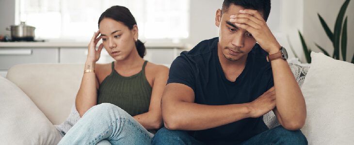 couple sitting on a couch looking upset over alimony